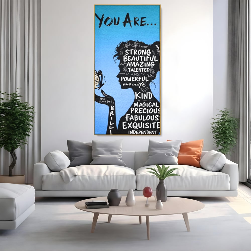Tablou canvas cu tablou motivational cu portret de femeie si cuvinte, in rama de aluminiu auriu, pe perete intr-un living